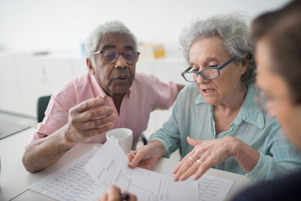 Black man with white hair, White woman with grey hair and glasses, and younger person looking at papers.